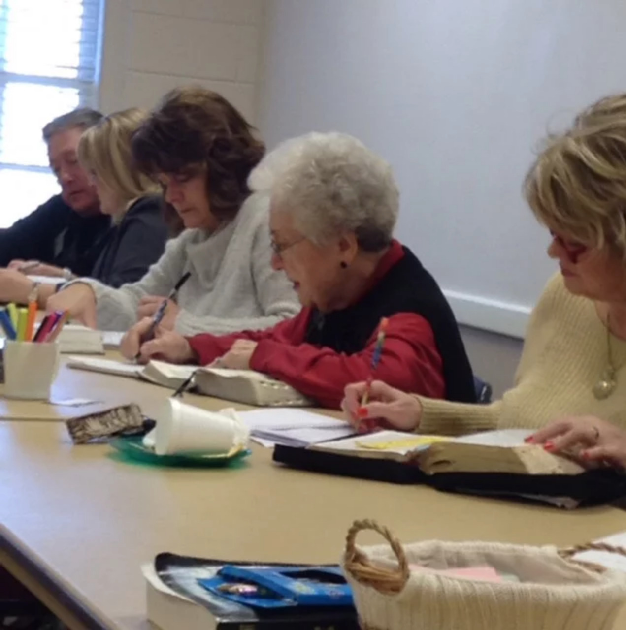 Adults taking notes at a Bible Study