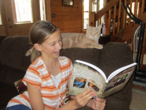 Girl holding Furry Philosophy book up so cat can see